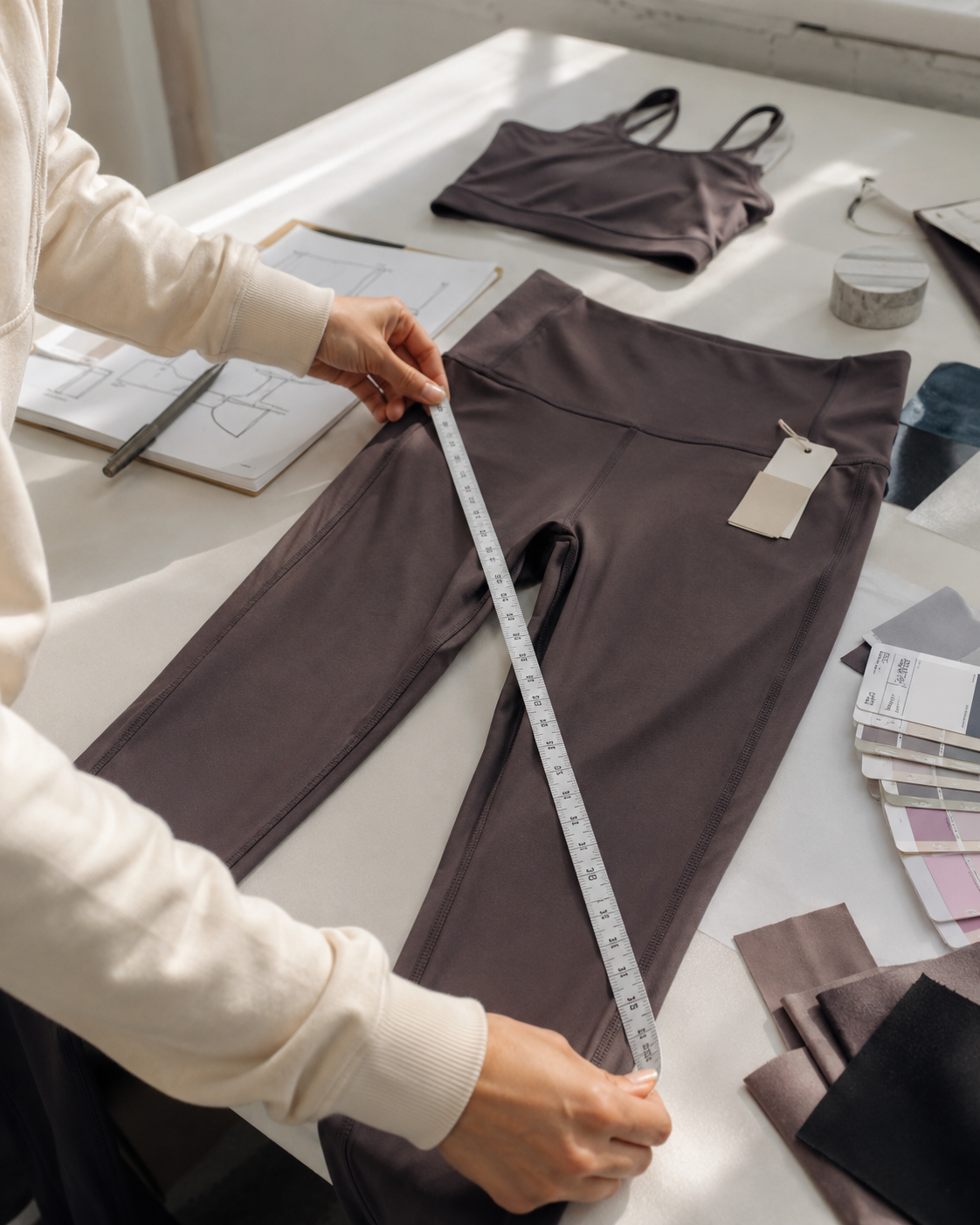 Quality inspector checking activewear measurement tolerances using calibrated steel tape