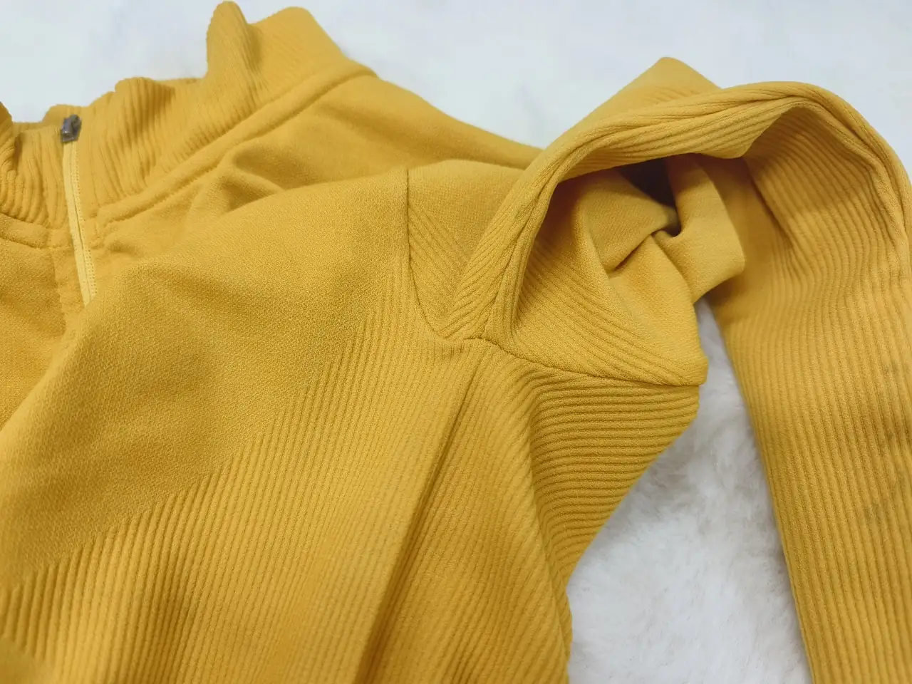 Close-up of the underarm junction in a long-sleeve knitted performance top