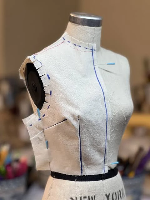 Technical cross-section illustrating tubular seamless tank body, neckline, armhole and shoulder construction interfaces